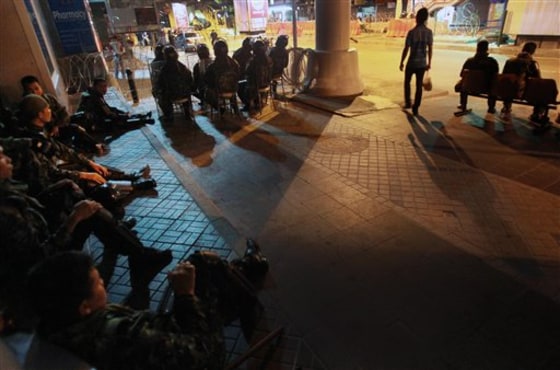 A Thai man carries home dinner as he passes by closed shops and Thai soldiers at an empty bus stop Friday in Bangkok.